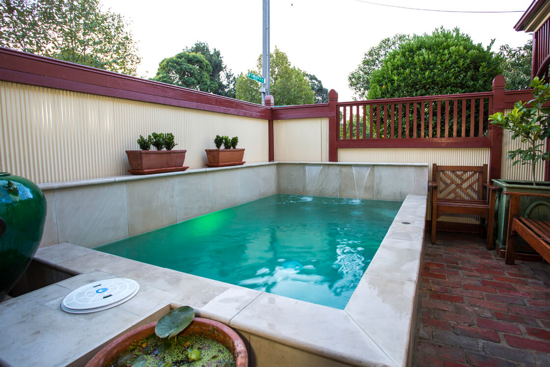Plunge pool with water spouts and sandstone edging in private courtyard
