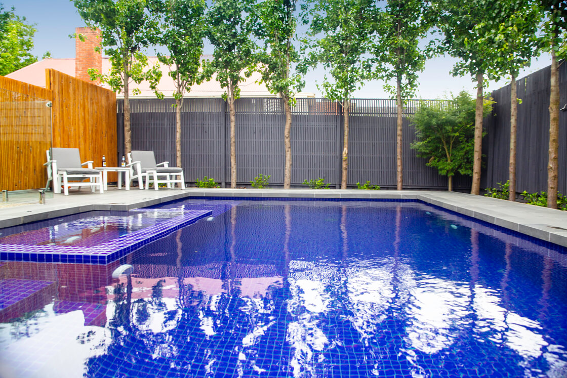 Pool with dark blue tiles and contemporary seating area