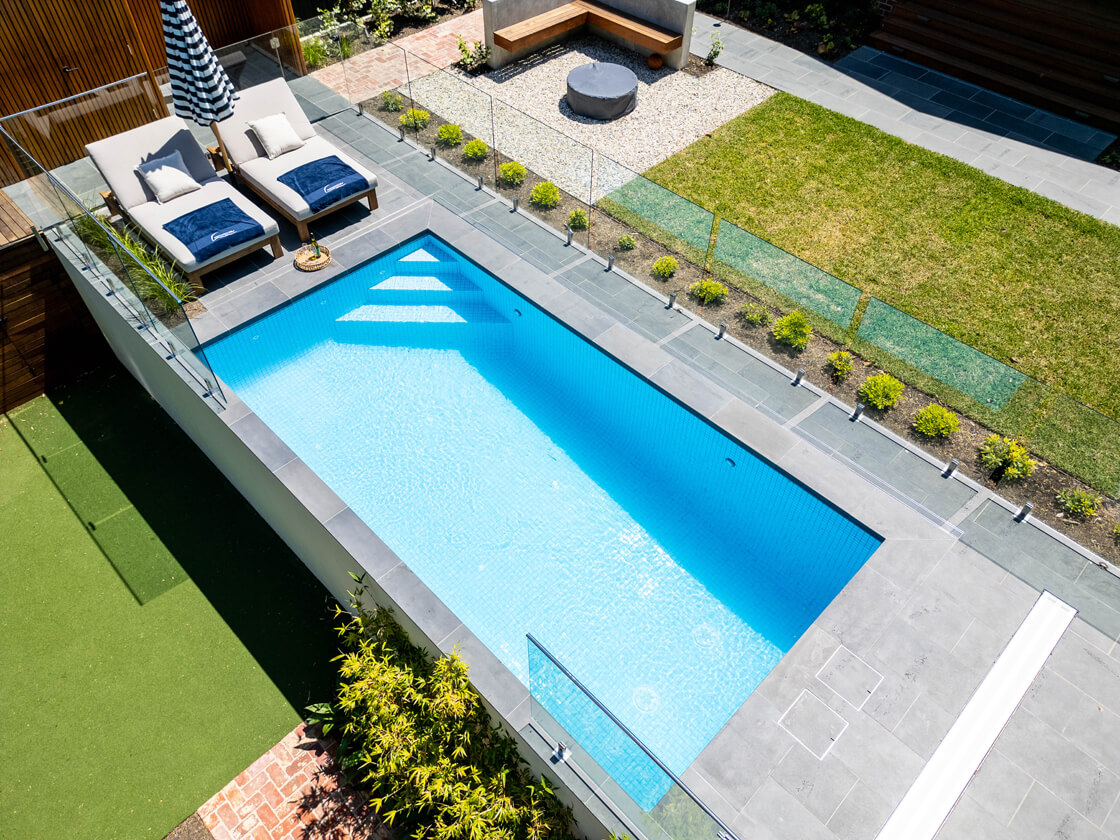 Aerial view of courtyard lap pool with pool lounges and modern paving
