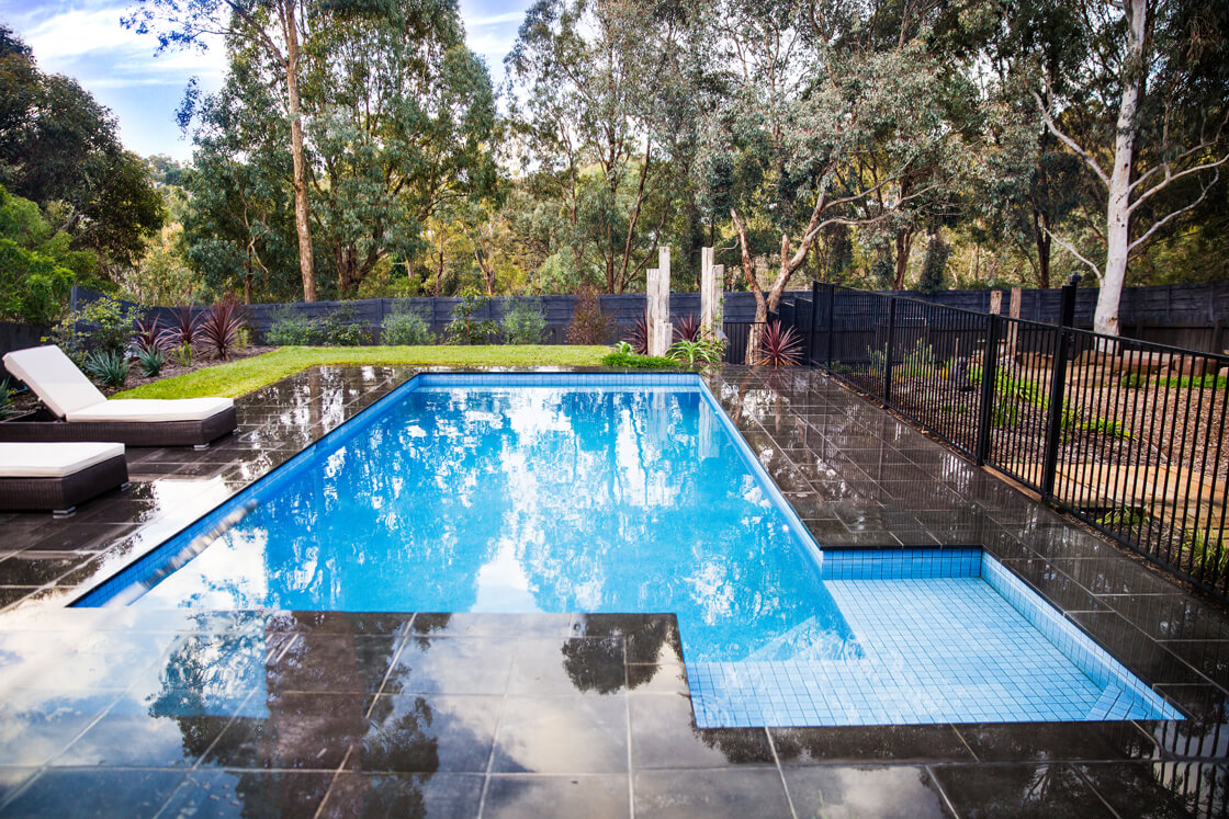Rectangular pool with glossy black tiles and surrounding eucalyptus trees