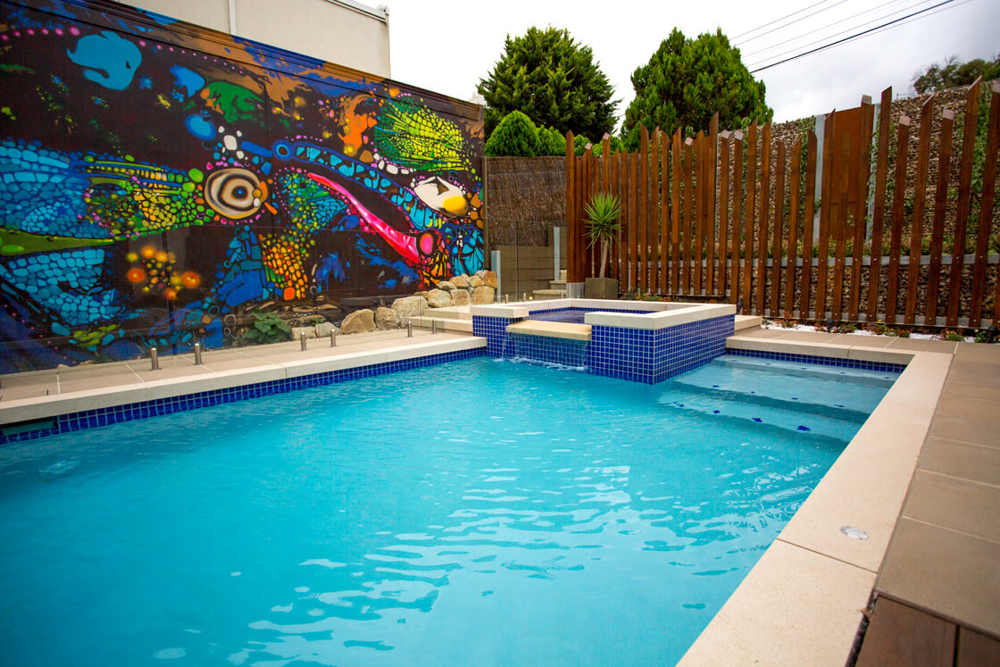 Bright mosaic mural beside spa and pool with blue tile features