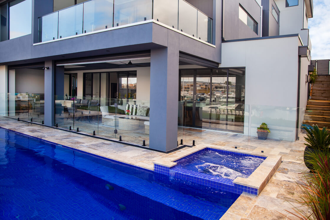 Lap pool with spa next to glass-walled modern marina home