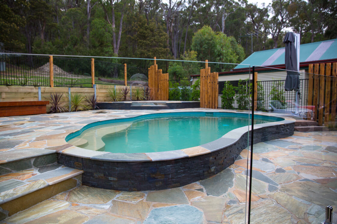 Curved pool with natural stone paving in bushland setting