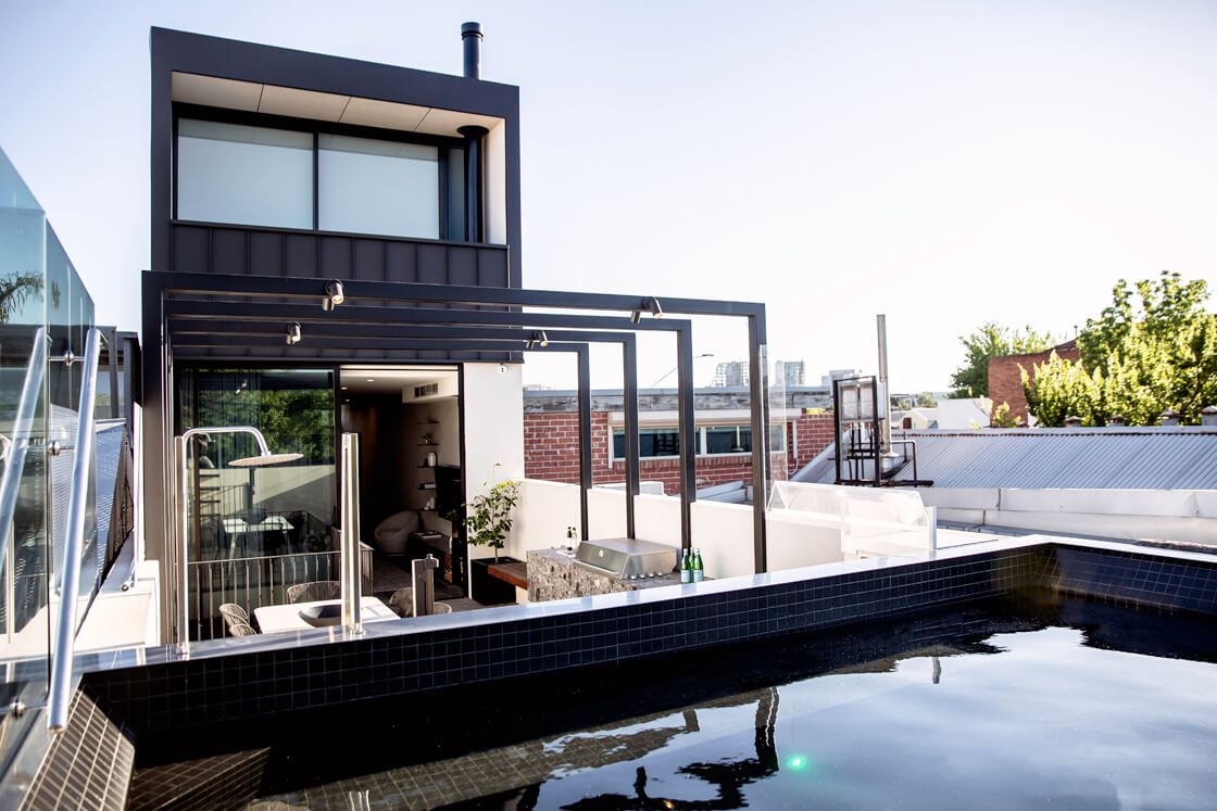 Black tiled rooftop pool on terrace beside modern city townhouse