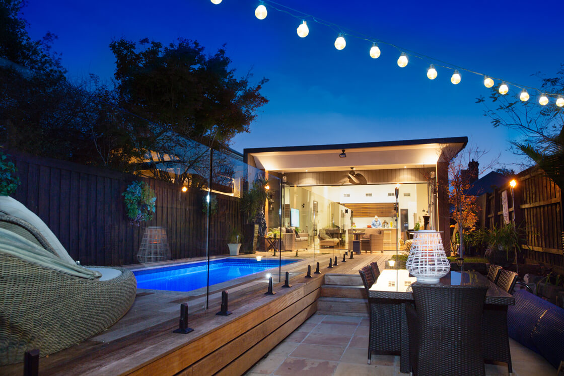 Courtyard pool with string lights, glass fencing and outdoor dining