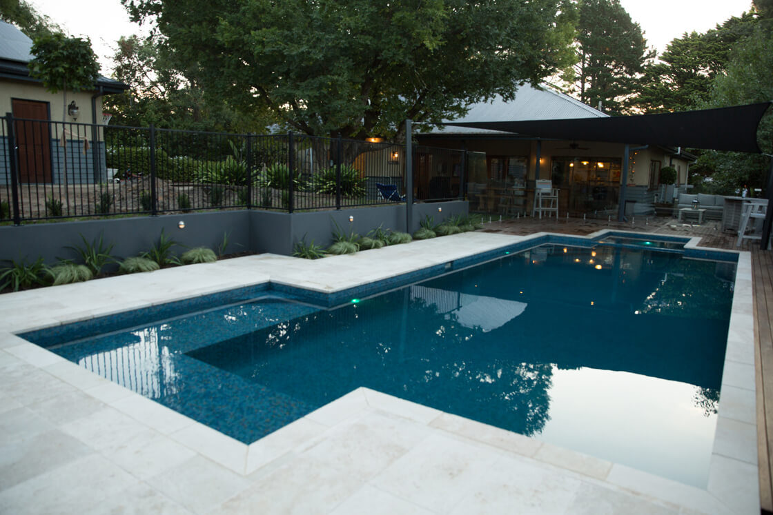 Tiled pool surrounded by mature trees and traditional garden elements