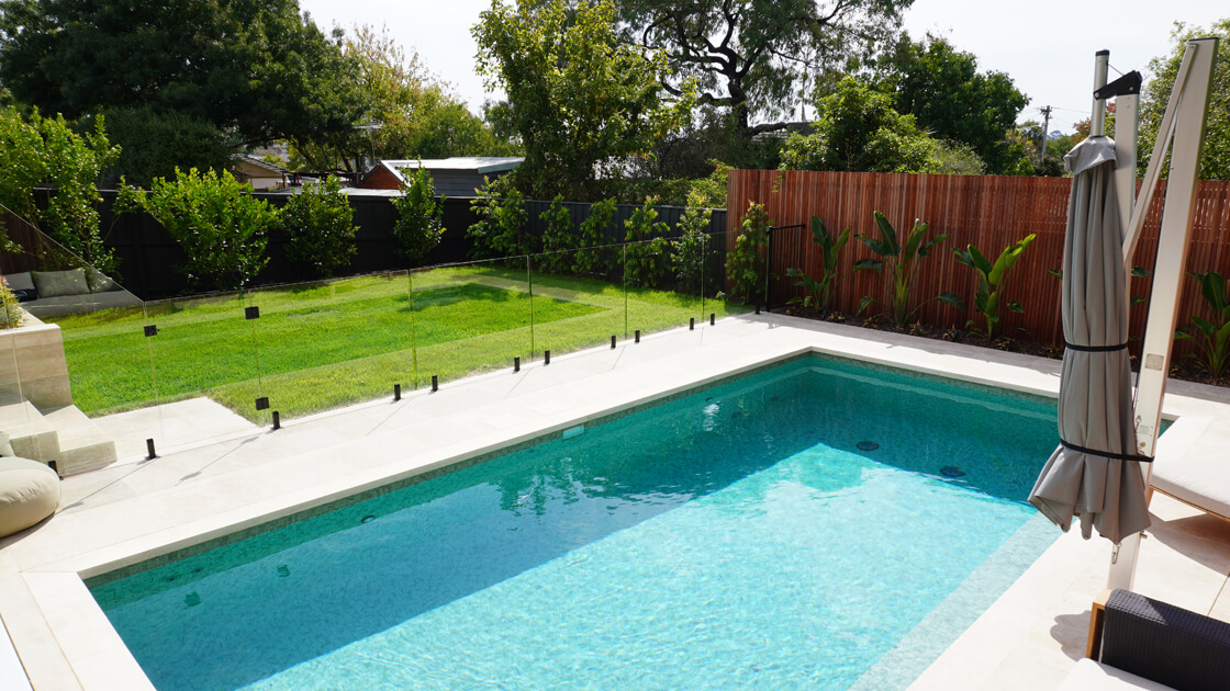 Rectangular pool with glass fencing and landscaped grass area