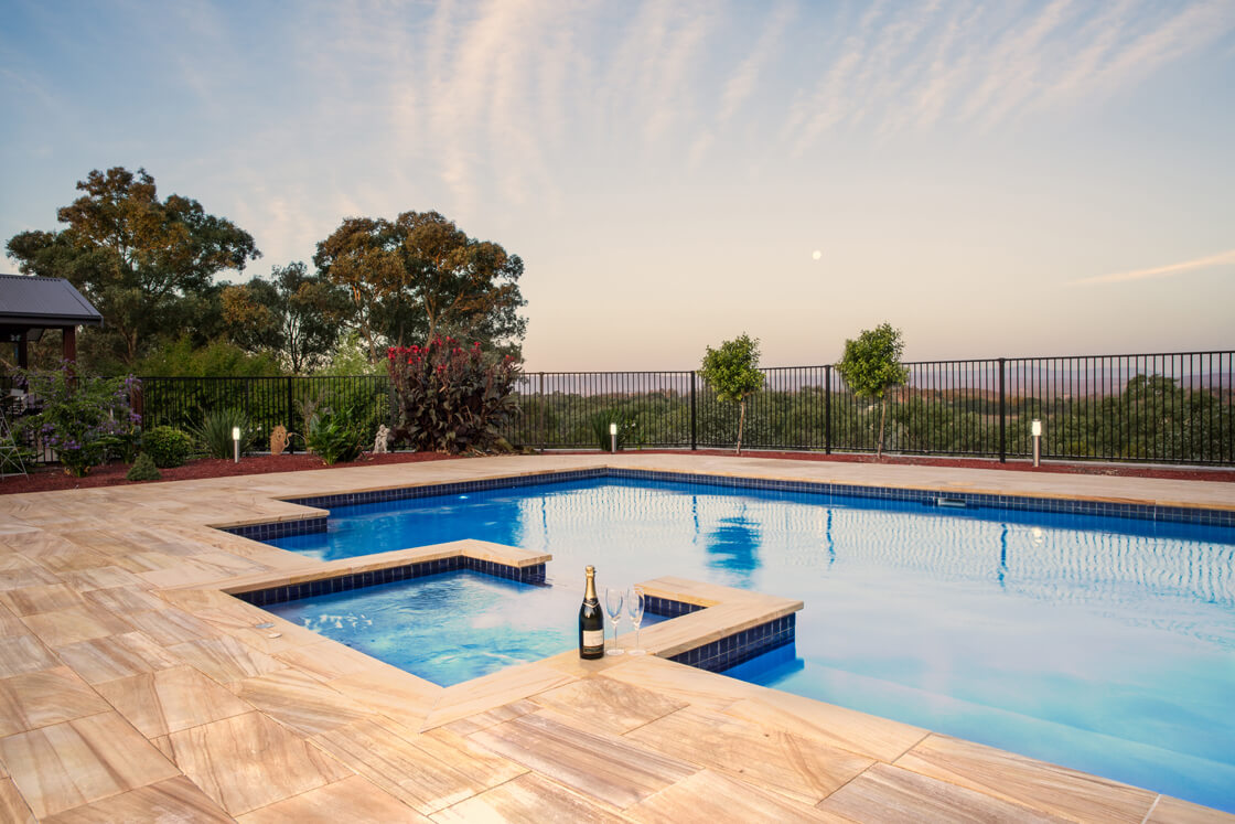 Pool and spa with sunset views, stone tiles and bottle of champagne