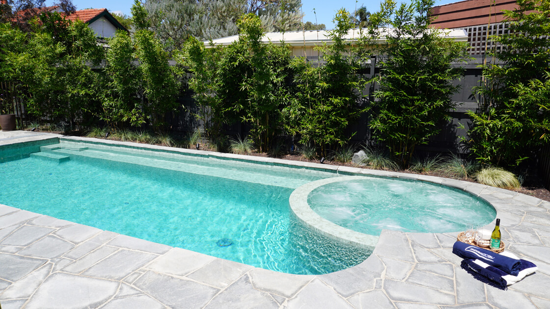 Lap pool with adjoining spa, bamboo screening and stone paving