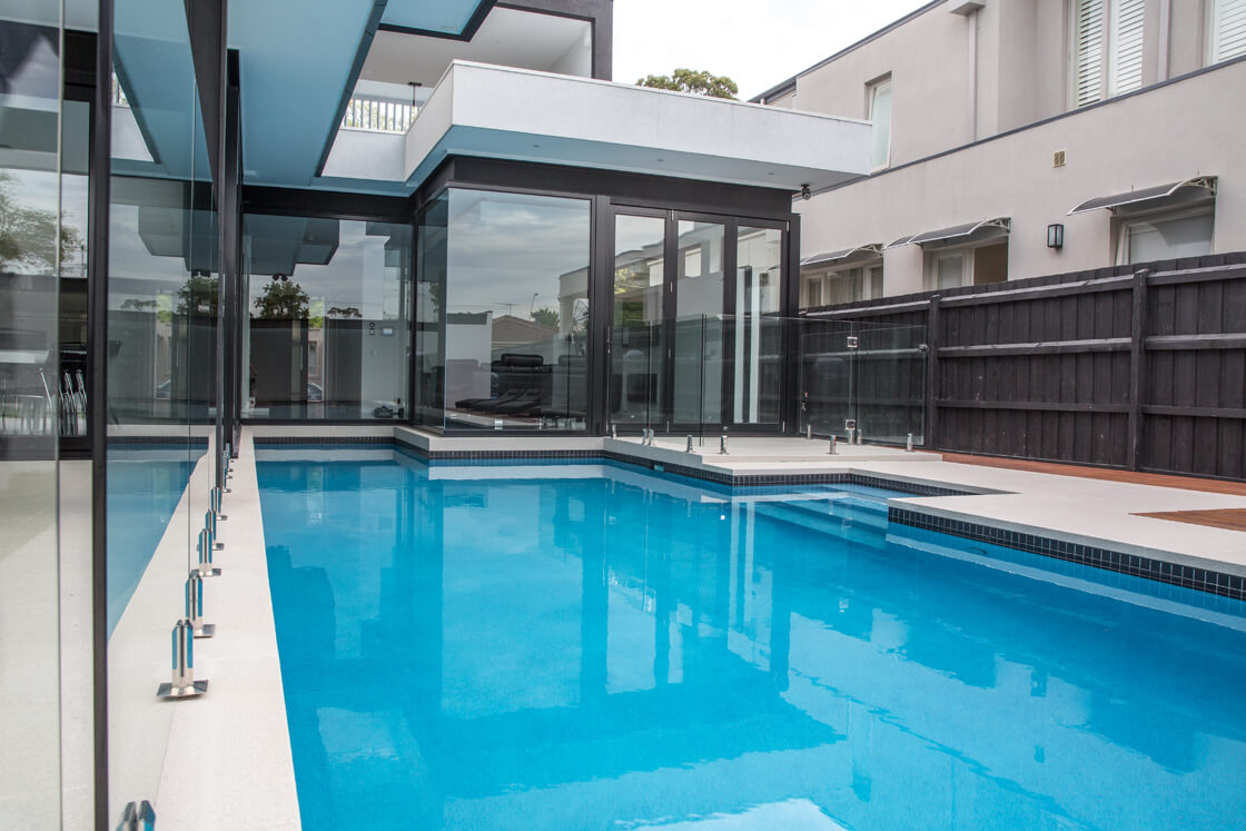 Contemporary pool next to a modern glass-walled home with clean lines