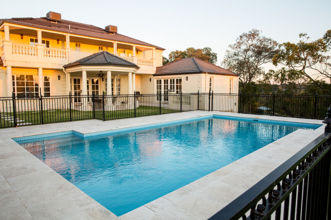 Luxury home with formal fenced pool and soft sunset lighting
