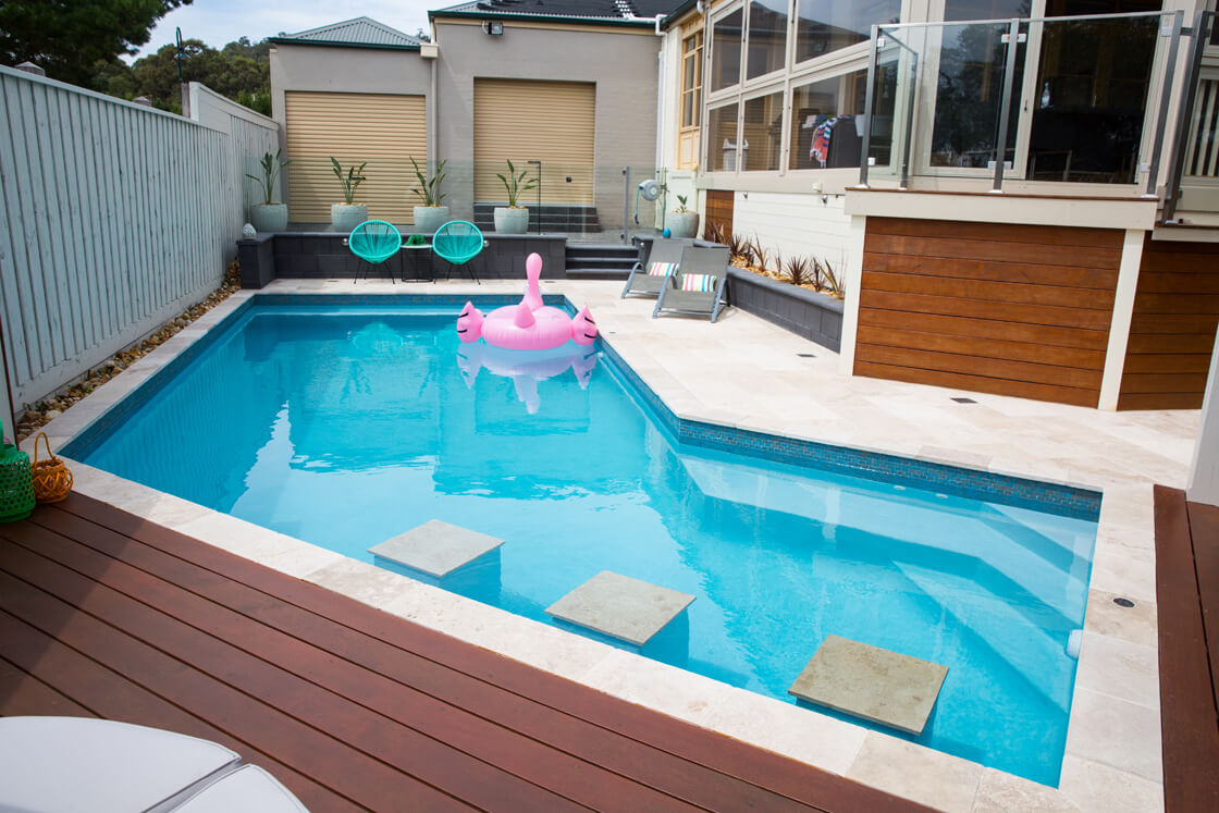 Small tiled pool with concrete stepping stones and pink flamingo inflatable